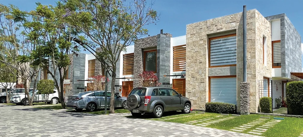 Fotografía de Maison Domaine: casas de piedra y madera sobre un camino adoquinado, con vehículos estacionados.