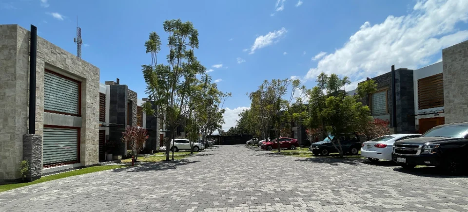 Fotografía de Maison Domaine: fila de casas de piedra con persianas enrollables y vehículos en el camino adoquinado.