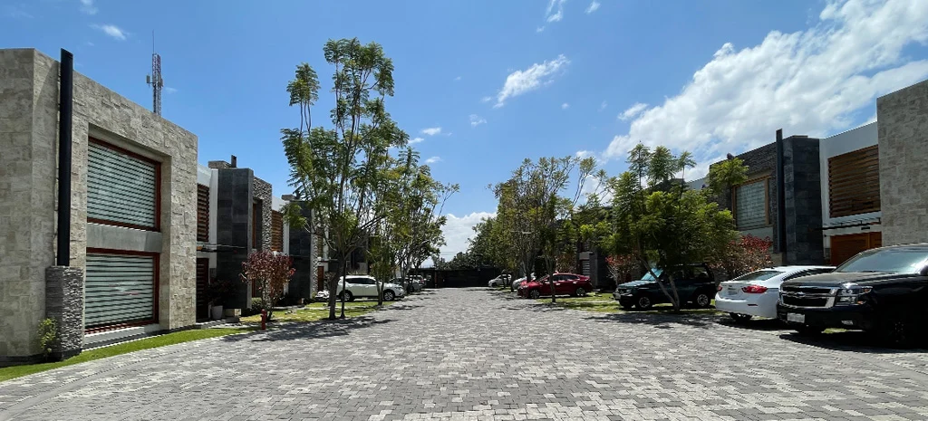 Fotografía de Maison Domaine: fila de casas de piedra con persianas enrollables y vehículos en el camino adoquinado.