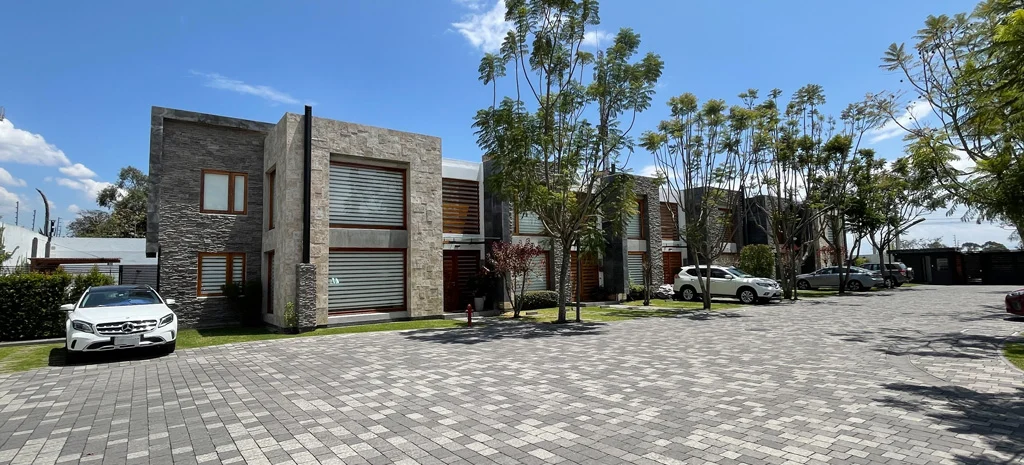Fotografía de Maison Domaine: casas de dos pisos con piedra y madera, y un vehículo blanco estacionado al frente.