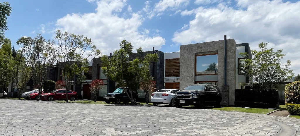 Fotografía de Maison Domaine: vista de calle con casas de piedra y madera, vehículos estacionados y árboles.