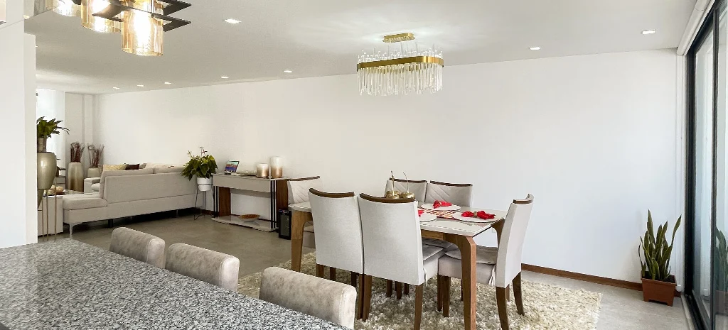 Fotografía del comedor de Kiyomi: mesa de madera con sillas claras, lámpara de cristal y ventanal lateral.