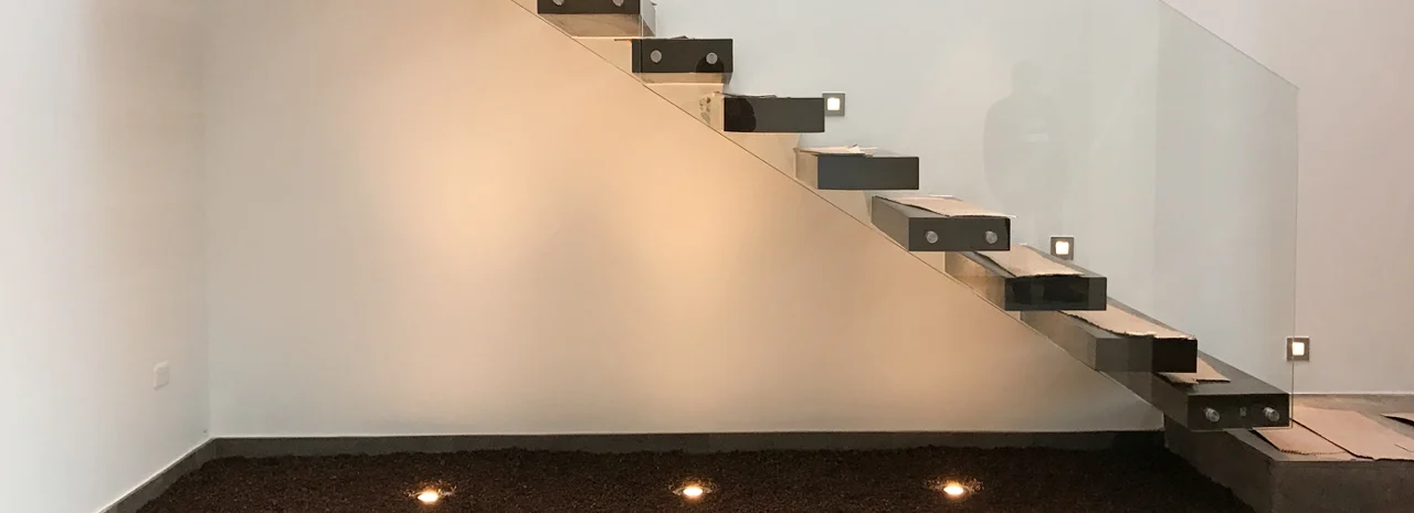 Fotografía de Domaine Cuatro: escalera de peldaños volados con barandilla de vidrio y luces empotradas en el piso.