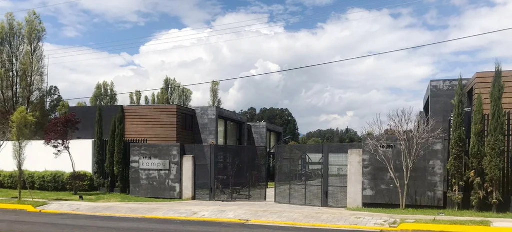 Fotografía de Villa Kampú: fila de casas de dos pisos con piedra oscura y madera, frente a un camino de adoquín.
