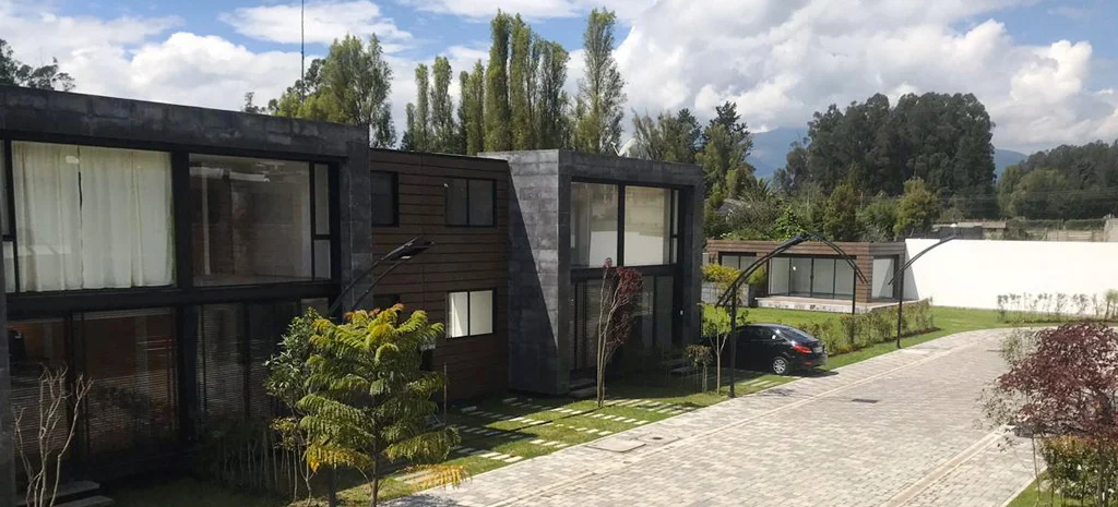 Fotografía de Villa Kampú: casa de piedra oscura con madera y un vehículo negro estacionado junto al camino.