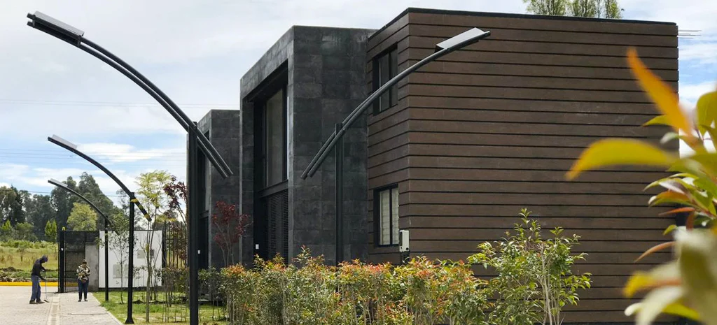 Fotografía de Villa Kampú: casas de piedra oscura y madera frente a postes de luz, césped y arbustos.